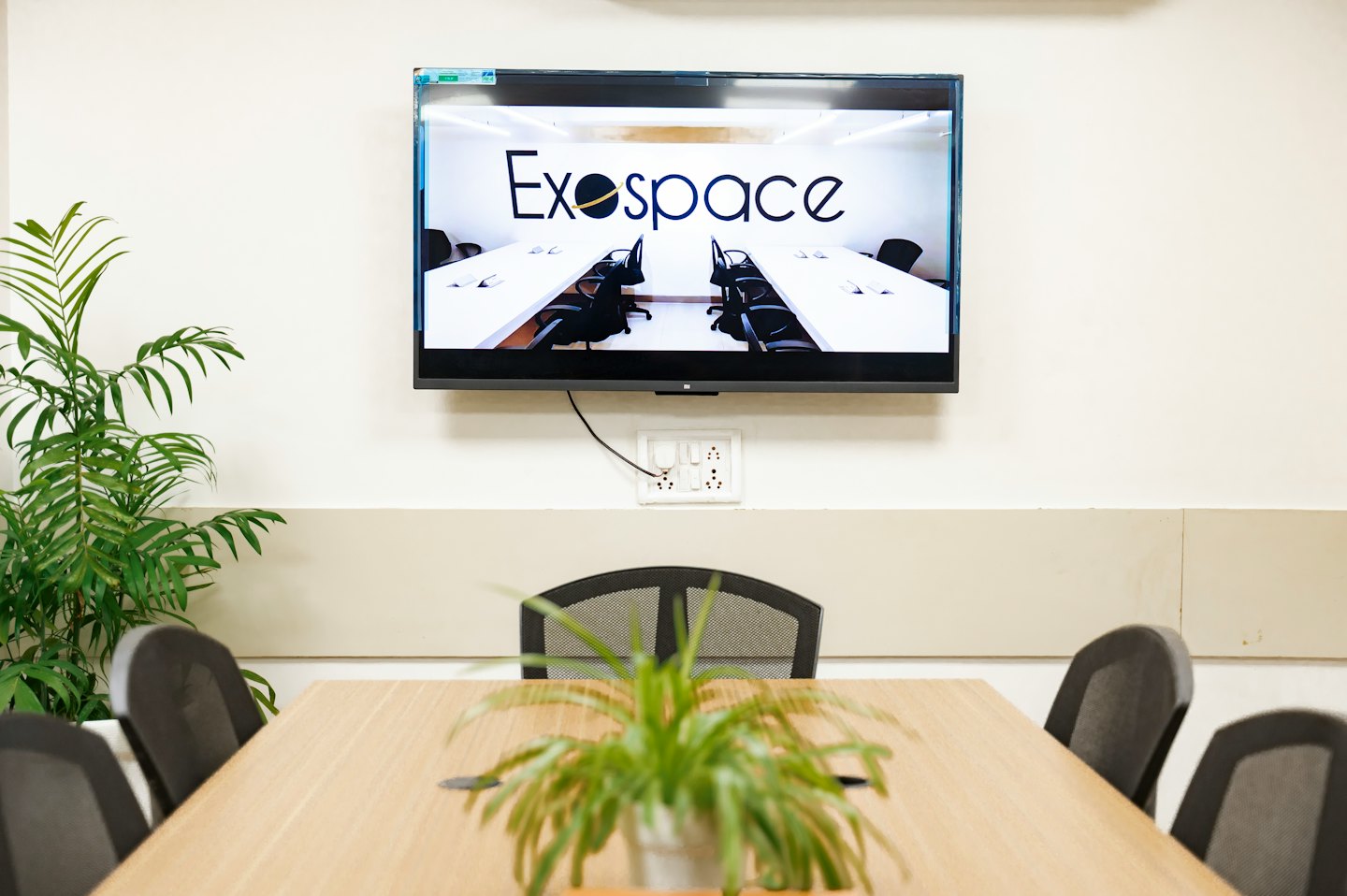 Sala de juntas corporativa con mesa de madera y monitor de pared.
