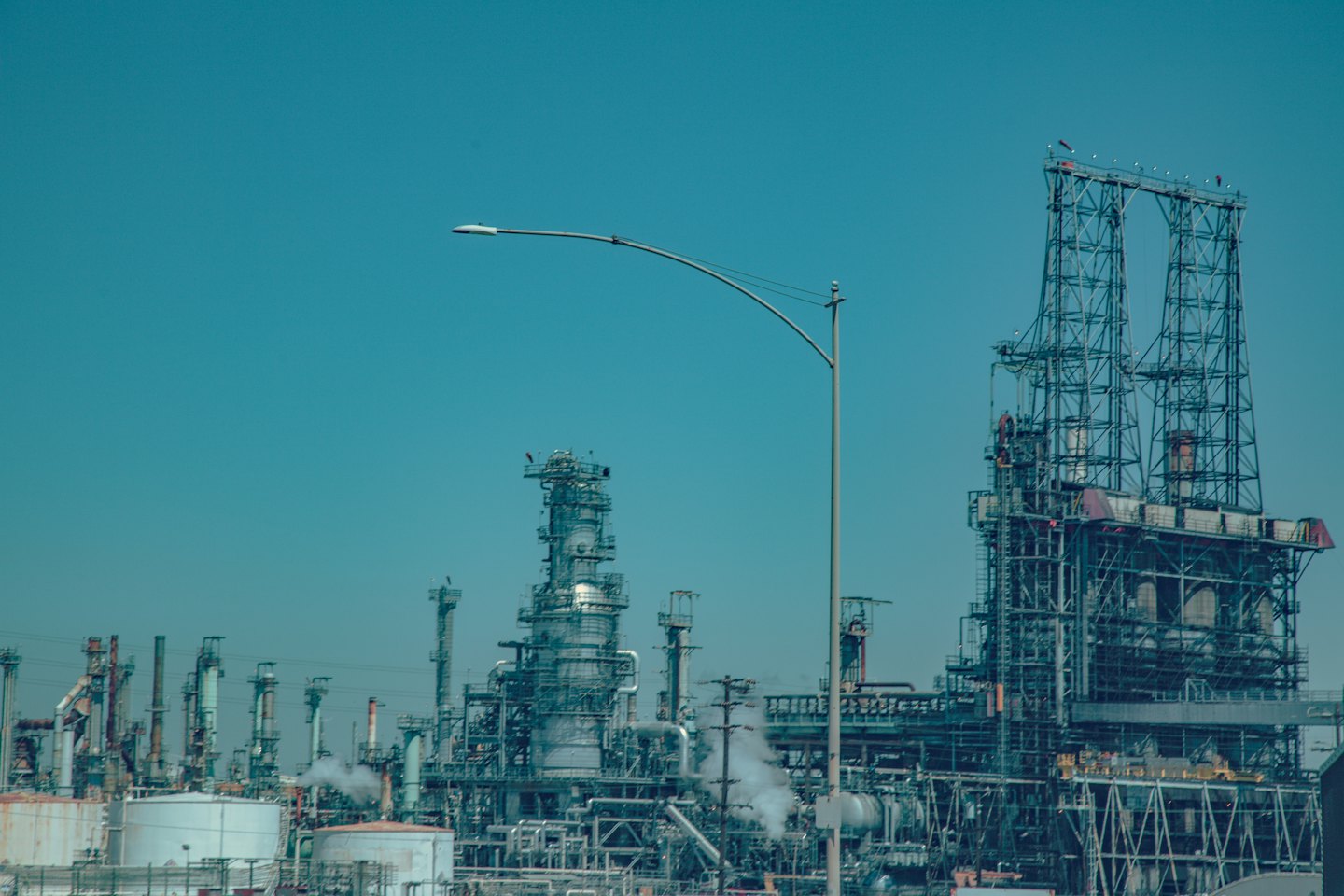 Complejo de refinería industrial con torres altas y tuberías bajo cielos despejados.
