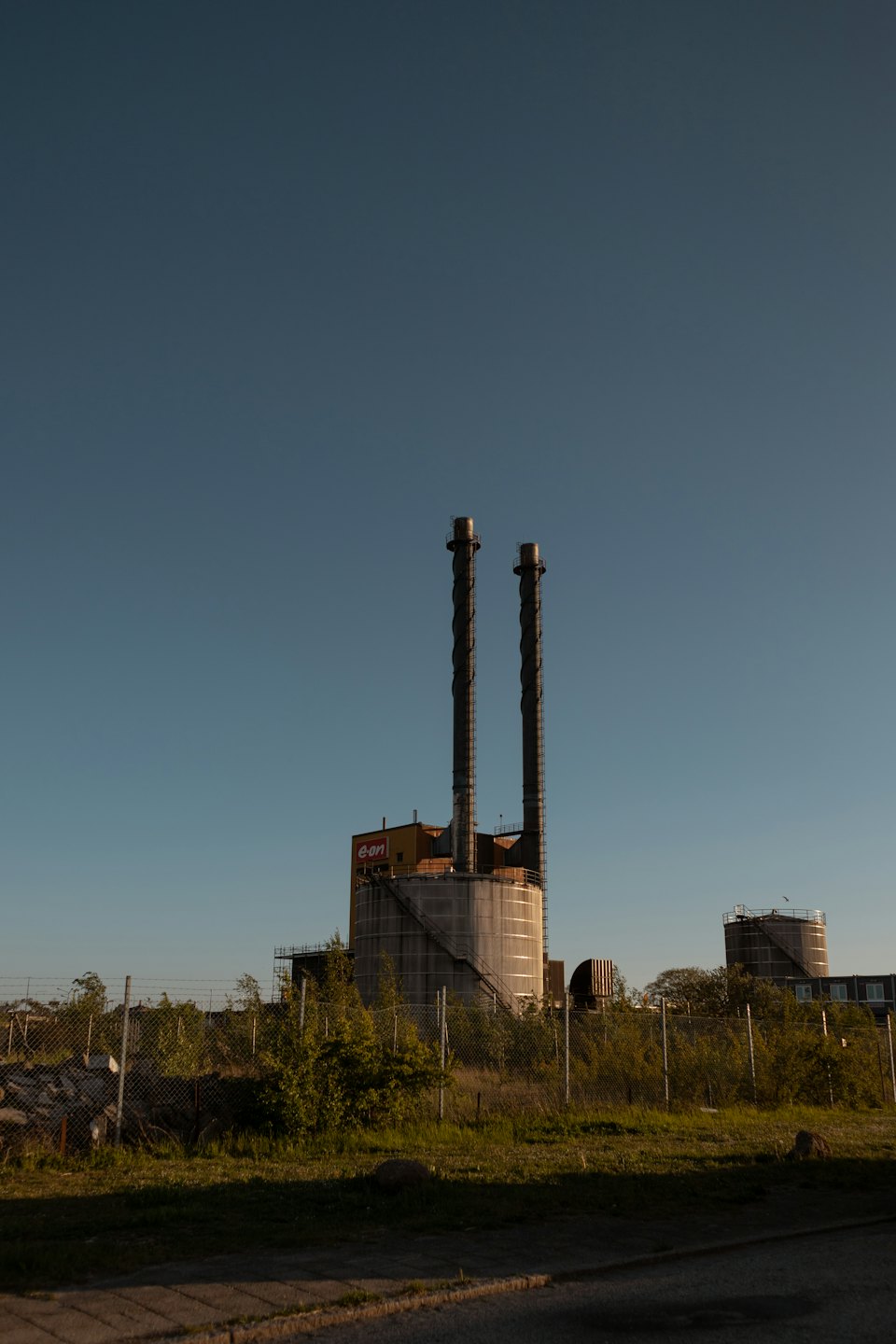 Chimeneas de una central eléctrica industrial con un edificio coronado de amarillo.