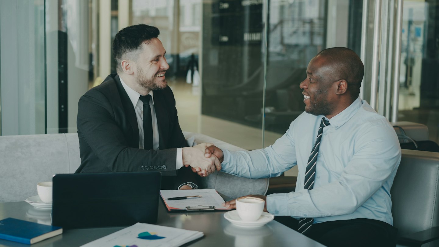 Dos profesionales de negocios se dan la mano sobre una mesa de conferencias.